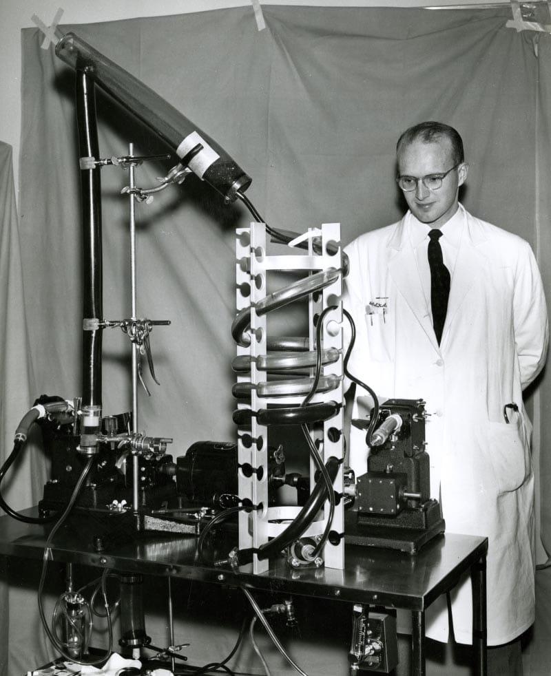 Dr. Richard DeWall in November 1956 with the heart-lung machine called a bubble oxygenator, which he developed. Used during heart surgery, the inexpensive and simple arrangement of cylinders and tubing rerouted the patient's blood, mixing it with oxygen. (Photo courtesy of University of Minnesota Archives)